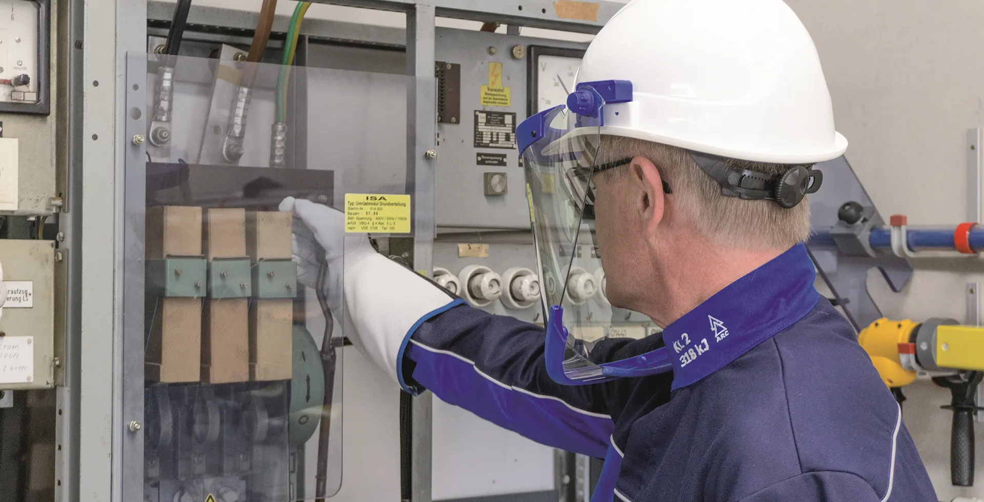 Técnico con careta y guantes dieléctricos frente a tablero eléctrico